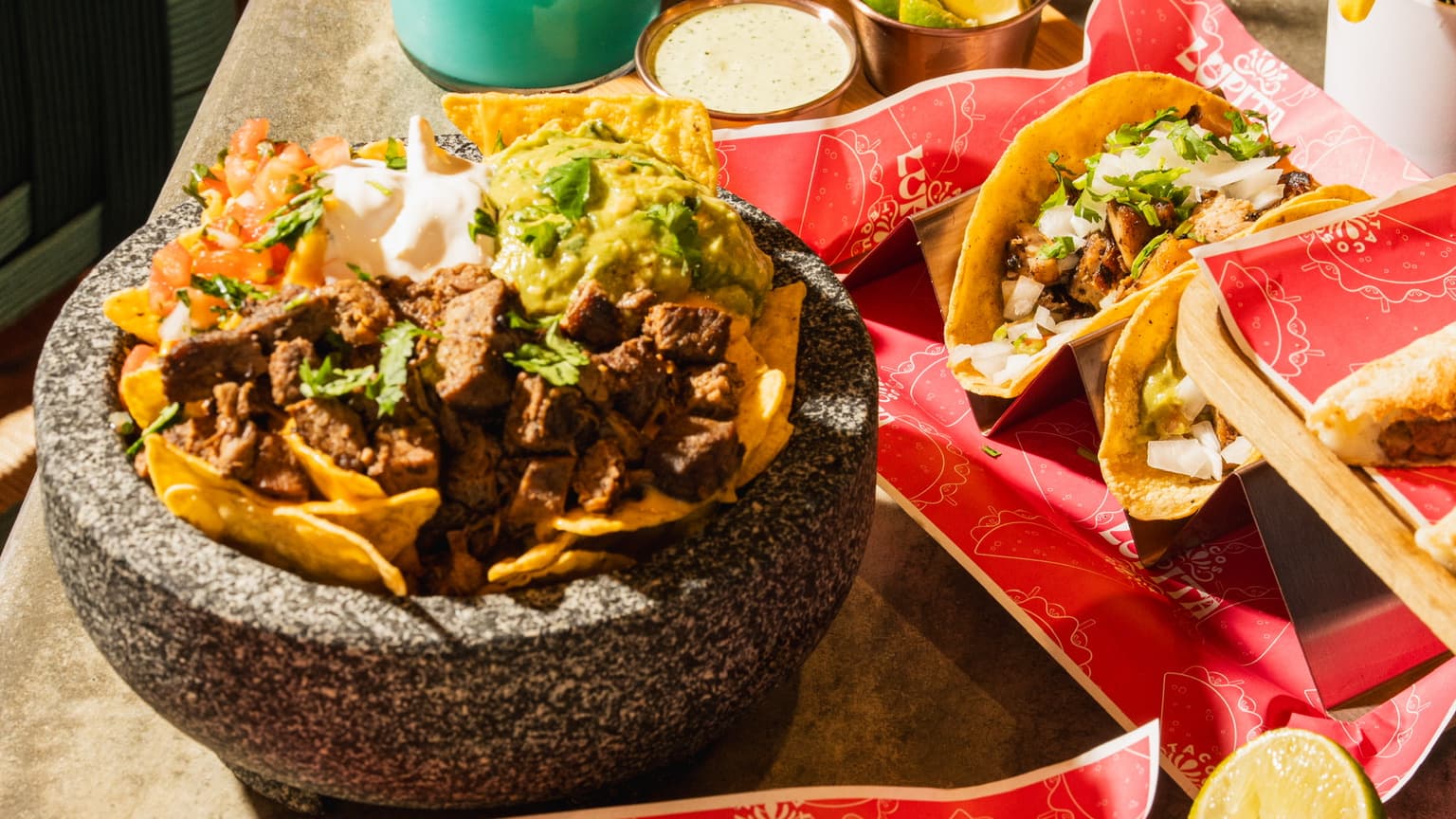 A loaded plate of nachos and tacos on a colorful Mexican-patterned background
